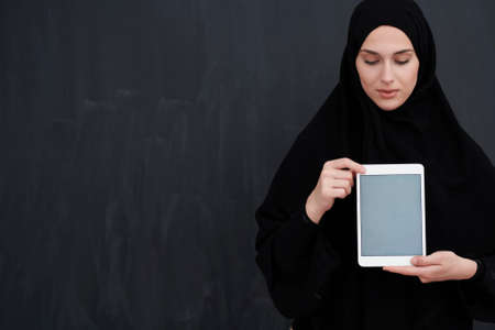 Young Arab businesswoman in traditional clothes or abaya holding tablet computerの写真素材