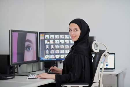 Muslim female graphic designer working on computer using graphic tablet and two monitorsの写真素材