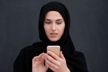 Young muslim businesswoman in traditional clothes or abaya using smartphoneの写真素材