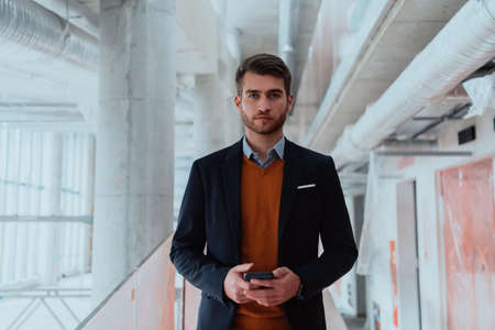businessman architect using a smartphone while overseeing the construction siteの写真素材
