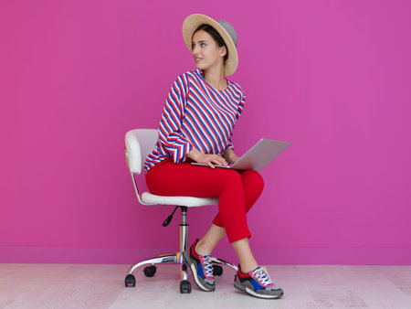 Portrait of young woman sitting on the chair and holding laptop on the lap