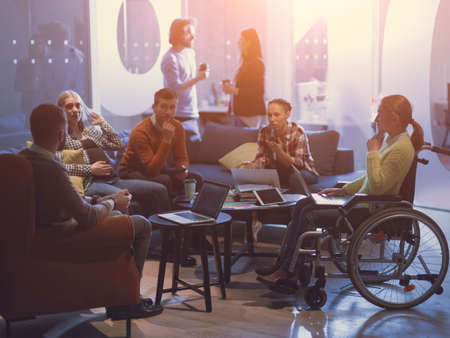 Handicapperd businesswoman in a wheelchair on meeting with her diverse business team brainstorming at officeの写真素材