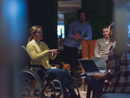 Businesswoman in wheelchair having business meeting with team at modern officeの写真素材
