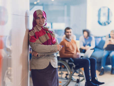 Muslim woman wearing hijab in office, Arabic business woman covered with headscarf smiling. Successful Arab businesswoman in modern office.の写真素材