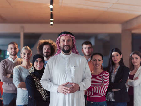 Portrait of multiracial diverse group of businesspeople team standing behind older Arab team leaderの写真素材