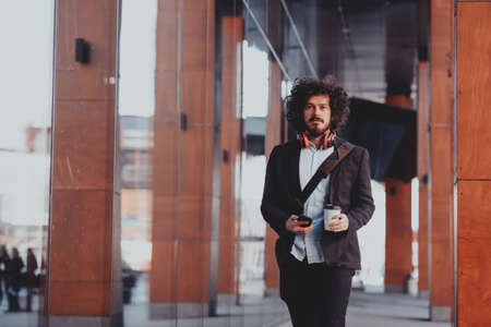 Happy young American holding a coffee. With headphones. Student boy.の写真素材