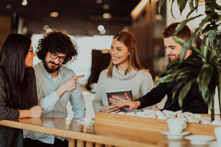 A group of people on a coffee break use laptops, tablets and smartphones while discussing new business projects. business concept.の写真素材