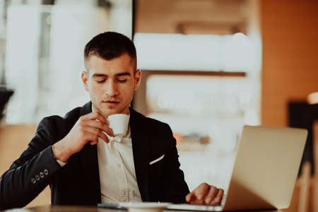 Happy business man sitting at cafeteria with laptop and smartphone.の写真素材