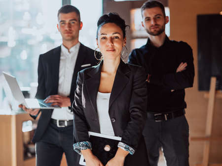 A portrait of a group of entrepreneurs in a modern office holding modern work equipment.の写真素材