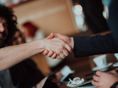 Business people or lawyers shaking hands finishing up meeting or negotiation in sunny office.の写真素材