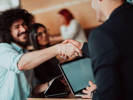 Business people or lawyers shaking hands finishing up meeting or negotiation in sunny office.の写真素材