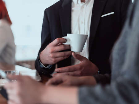 macro photo of a businessman in a cafe in a suit holding a cup of coffee.の写真素材