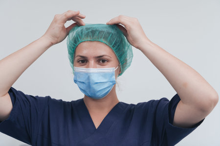 Close up of female doctor or scientist with a medical mask and surgical cap