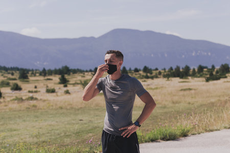 Young man and woman in protective masks running and doing exercises outdoors in the morning. Sport, Active life Jogging during quarantine. Covid-19 new normal. High quality photo. Selective focus.の写真素材