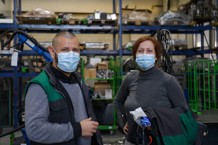 Industrial workers with face masks protected against corona virus discussing about production in factory. People working during COVID-19 pandemic.の写真素材