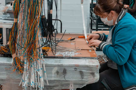 Industrial worker wearing a face mask due to a coronavirus pandemic solders cables from factory production equipmentの写真素材