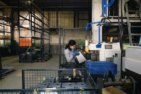 woman working in the metal industry in the production of new machines wears a face mask during work due to the coronavirus pandemicの写真素材