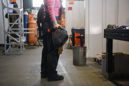 a portrait of a women welder holding a helmet and preparing for a working day in the metal industry