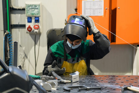 A woman employed in a modern factory for the production and processing of metals in a work uniform...