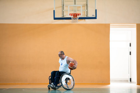 a war invalid in a wheelchair trains with a ball at a basketball club in training with professional sports equipment for the disabled. the concept of sport for people with disabilitiesの写真素材