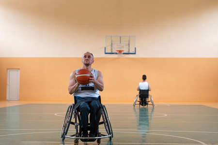 a photo of a war veteran playing basketball with a team in a modern sports arena. The concept of sport for people with disabilitiesの写真素材
