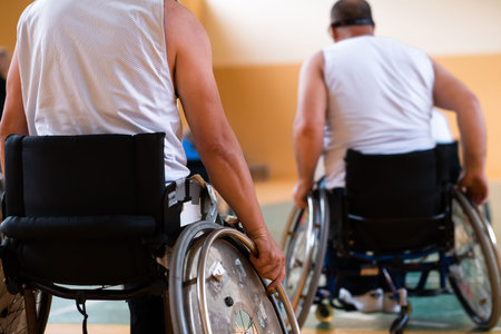 Close up photo of wheelchairs and handicapped war veterans playing basketball on the court