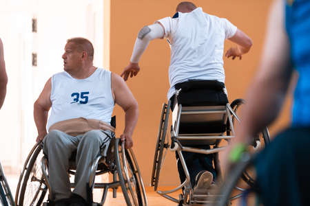 Close up photo of wheelchairs and handicapped war veterans playing basketball on the courtの写真素材