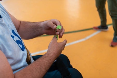 a disabled basketball player puts on a corset and bandages on his arms and fingers in preparation...