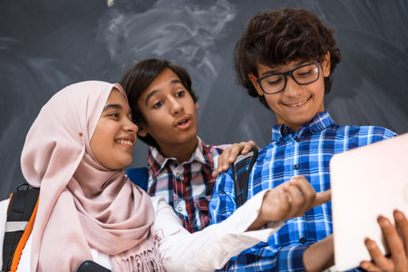 Arabic teenagers team, students group working together on laptop and tablet computer online...