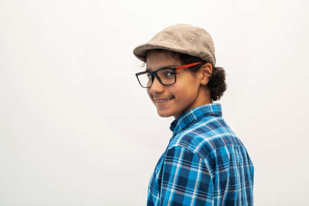 portrait of smart looking arab teenager with glasses wearing a hat in casual school look isolated on white copy spaceの写真素材