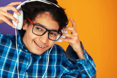 Teenage Boy Wearing Headphones And Listening To Music purple backgroundの写真素材