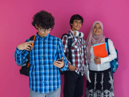 A group of Arab teenagers, a student team walking forward into the future and back to school the concept of a pink background. The concept of successful education for young people. Selective focusの写真素材