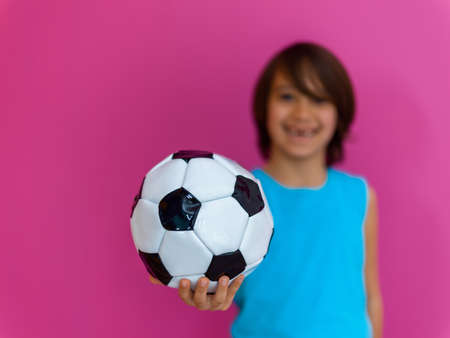 Portrait of young Arabic boy with soccer ball isolated against pink background and copy spaceの写真素材
