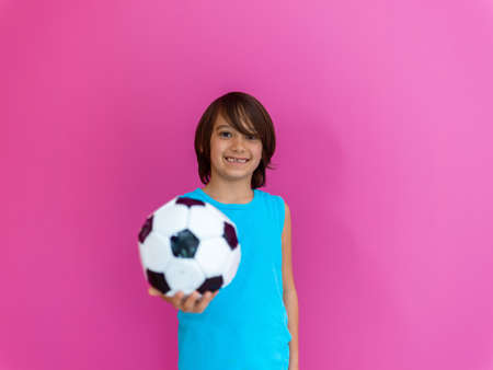 Portrait of young Arabic boy with soccer ball isolated against pink background and copy spaceの写真素材