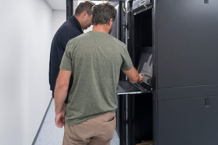 Technicians team updating hardware inspecting system performance in super computer server room or...