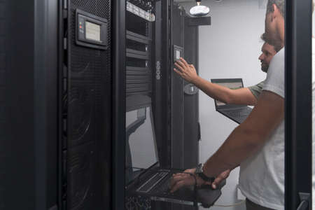 Technicians team updating hardware inspecting system performance in super computer server room or cryptocurrency mining farm.の写真素材