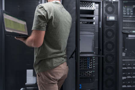 Data Center Engineer Using Laptop Computer Server Room Specialist Facility with Male System Administrator Working with Data Protection Network for Cyber Security or Cryptocurrency Mining Farm.の写真素材