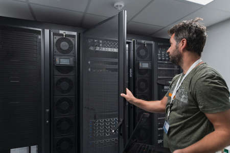 Data Center Engineer Usaing Keyboard on a Supercomputer Server Room Specialist Facility with Male System Administratorの写真素材
