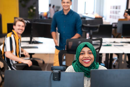 Multiethnic startup business team Arabian woman wearing a hijab on meeting in modern open plan office interior brainstorming, working on laptop and desktop computer. Selective focusの写真素材