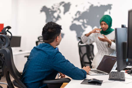 Multiethnic startup business team Arabian woman wearing a hijab on meeting in modern open plan office interior brainstorming, working on laptop and desktop computer. Selective focusの写真素材