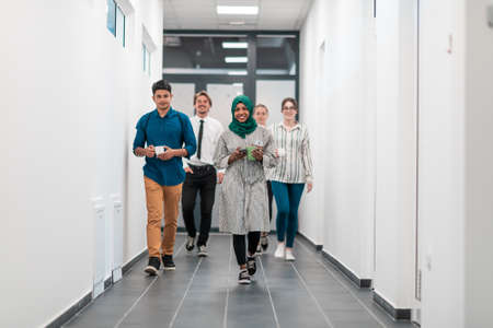 Multi-ethnic startup business team walking through the hallway of the building while coming back from a coffee breakの写真素材