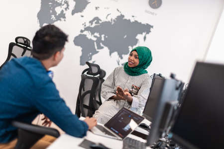 Multiethnic startup business team Arabian woman wearing a hijab on meeting in modern open plan office interior brainstorming, working on laptop and desktop computer. Selective focusの写真素材