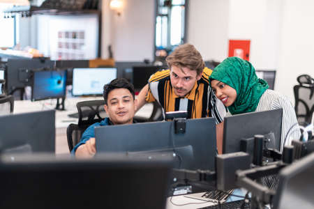 Multiethnic startup business team Arabian woman wearing a hijab on meeting in modern open plan office interior brainstorming, working on laptop and desktop computer. Selective focusの写真素材