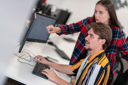 Business couple working together on project using tablet and desktop computer at modern open plan...