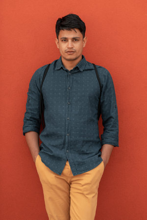 Startup business portrait of casual businessman with a blue shirt and backpack in front of red wall