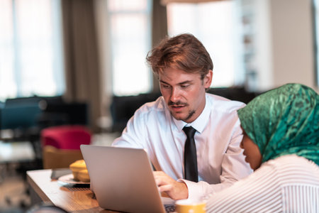 International multicultural business team.Man and muslim woman with hijab working together using smartphone and laptop coxation area at modern open plan startup officemputer in relaの写真素材