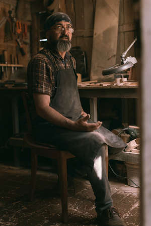 Spoon master in his workshop with wooden products and toolsの写真素材