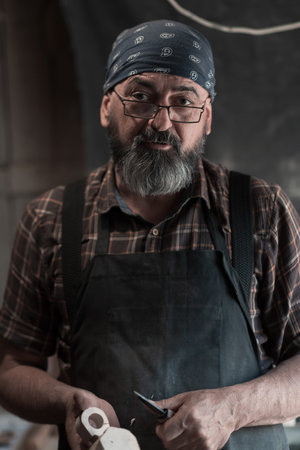 Spoon master in his workshop with wooden products and tools