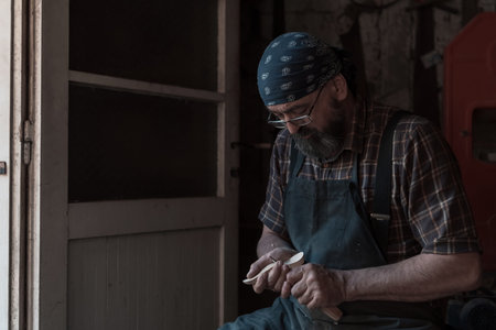 Spoon craft master in his workshop with handmade wooden products and tools working