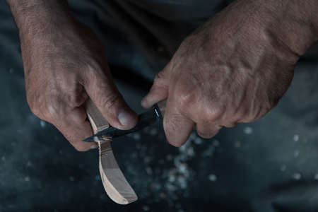 Hands carving spoon from wood, working with chisel close up. Wooden workshop. Process of making wooden spoonの写真素材